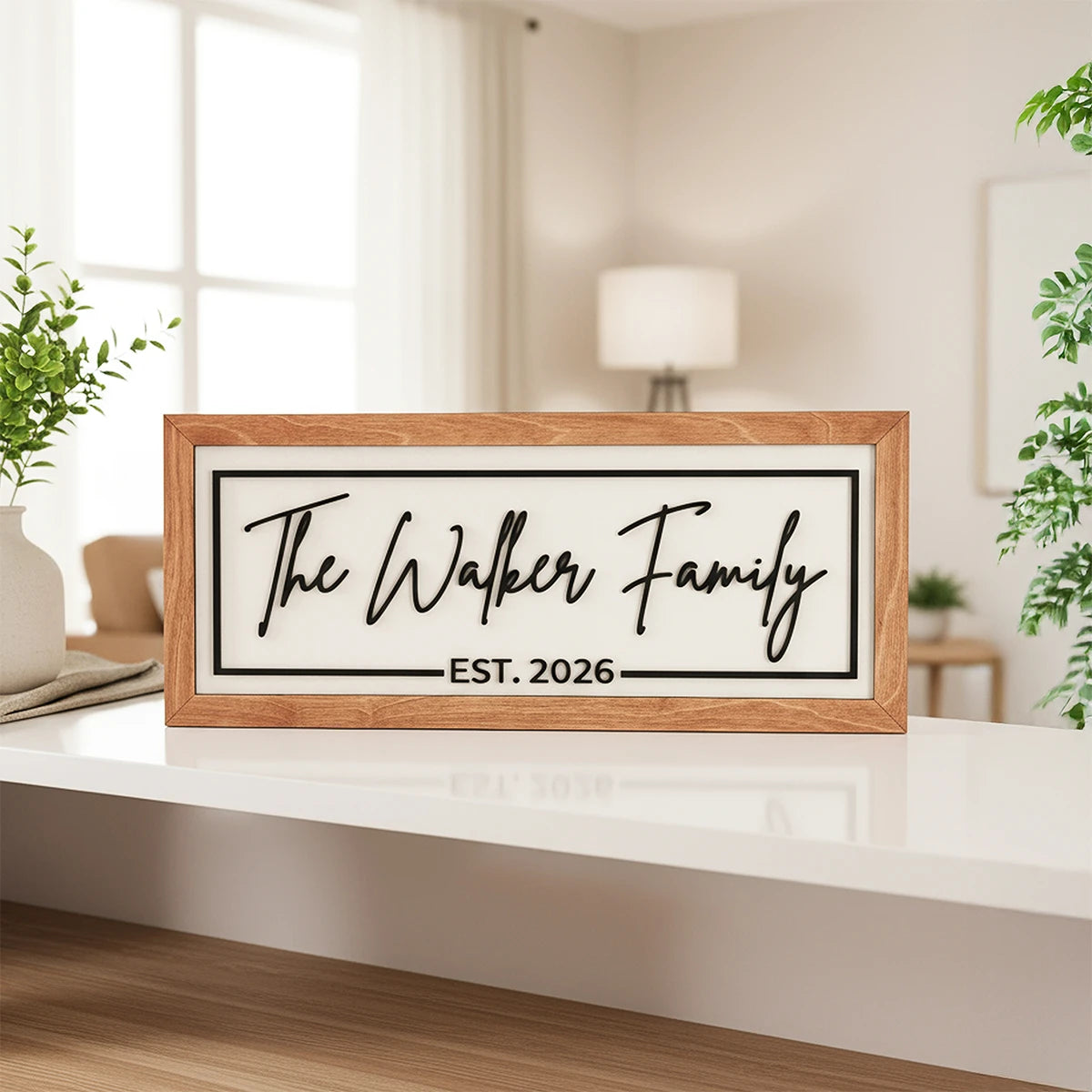 Framed sign with 'The Walker Family EST. 2026' on a white surface in a room with plants and a lamp.