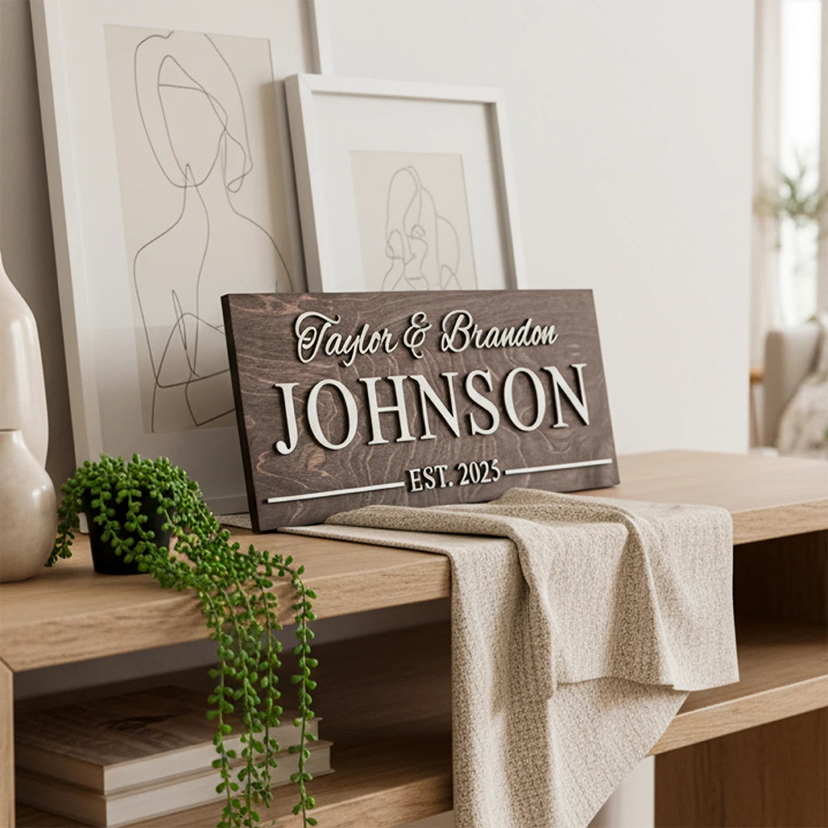 Wooden sign with 'Taylor & Brandon JOHNSON EST. 2023' on a wooden surface with decor elements.