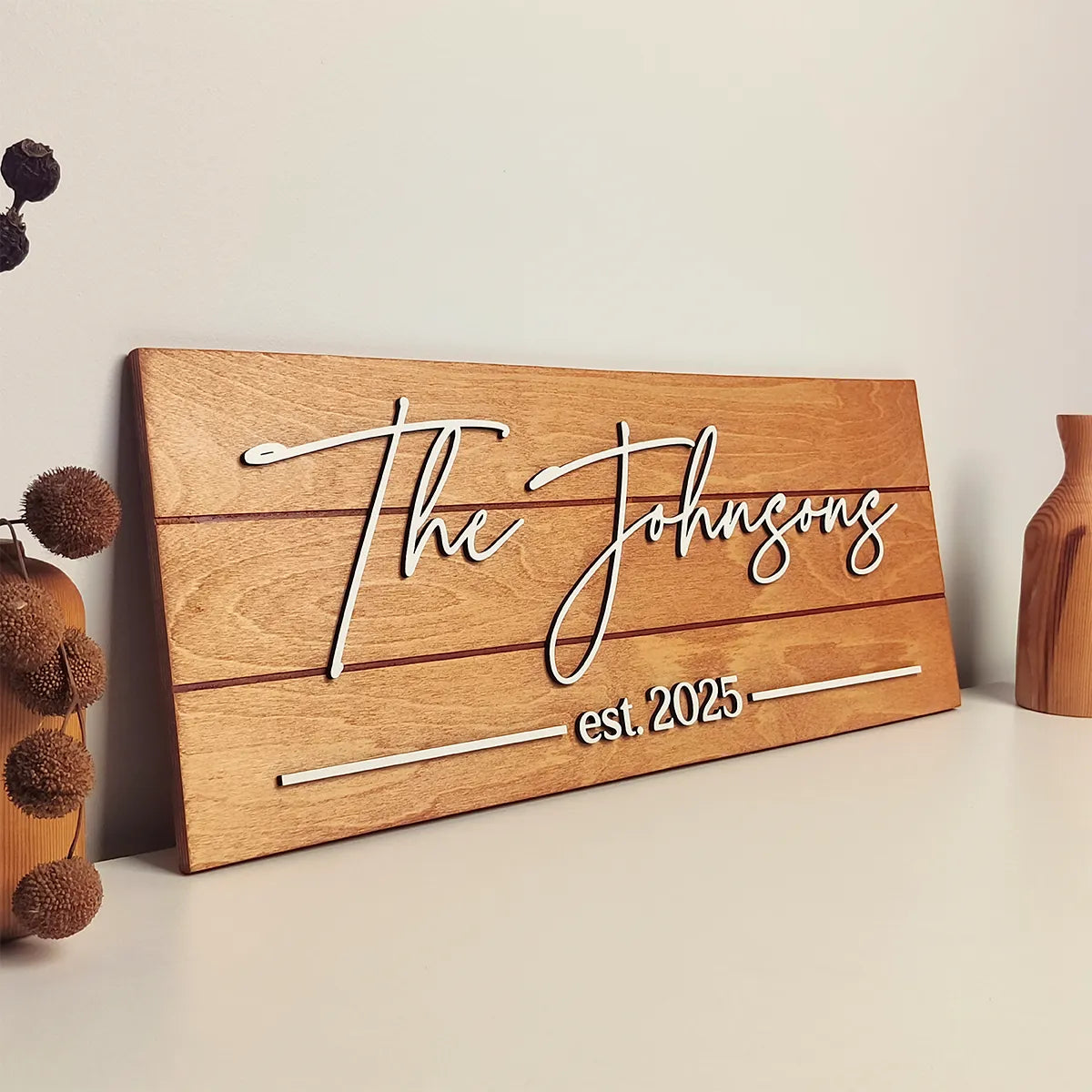 Wooden sign with 'The Johnsons est. 2025' on a neutral background